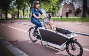 urban arrow family bicycle with woman riding and two children in the carriage